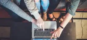 three person pointing the silver laptop computer