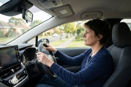 Femme reprenant confiance au volant après une annulation de permis, mains crispées sur le volant dans une voiture compacte moderne