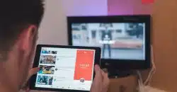 man browsing tablet sitting in front of TV