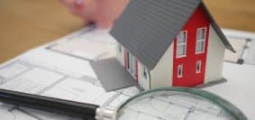 white and red wooden house beside grey framed magnifying glass